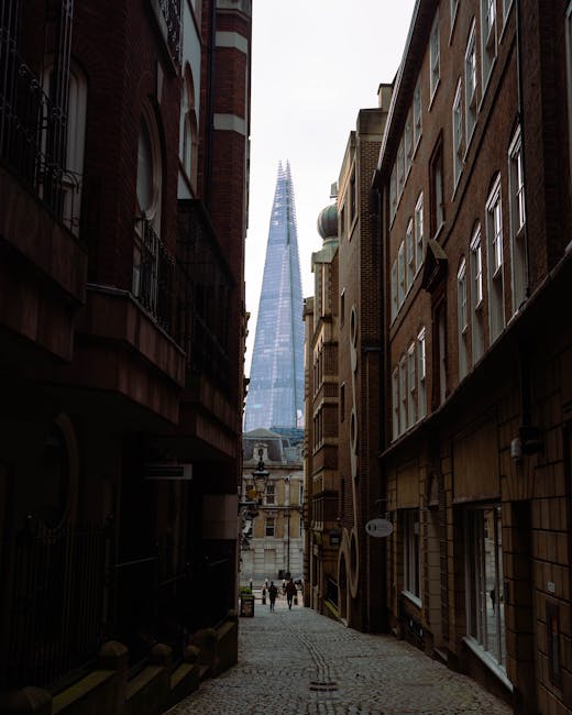 A narrow residential street in Rotherhithe lined with white and brick-fronted terraced houses, each with front doors and small potted plants or shrubs placed outside. The street features cobblestone p